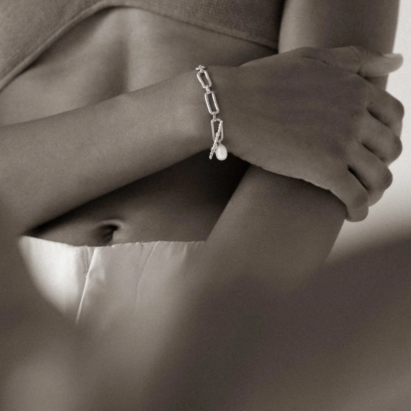 Silver bracelet with a pearl on a person's wrist, blurred background