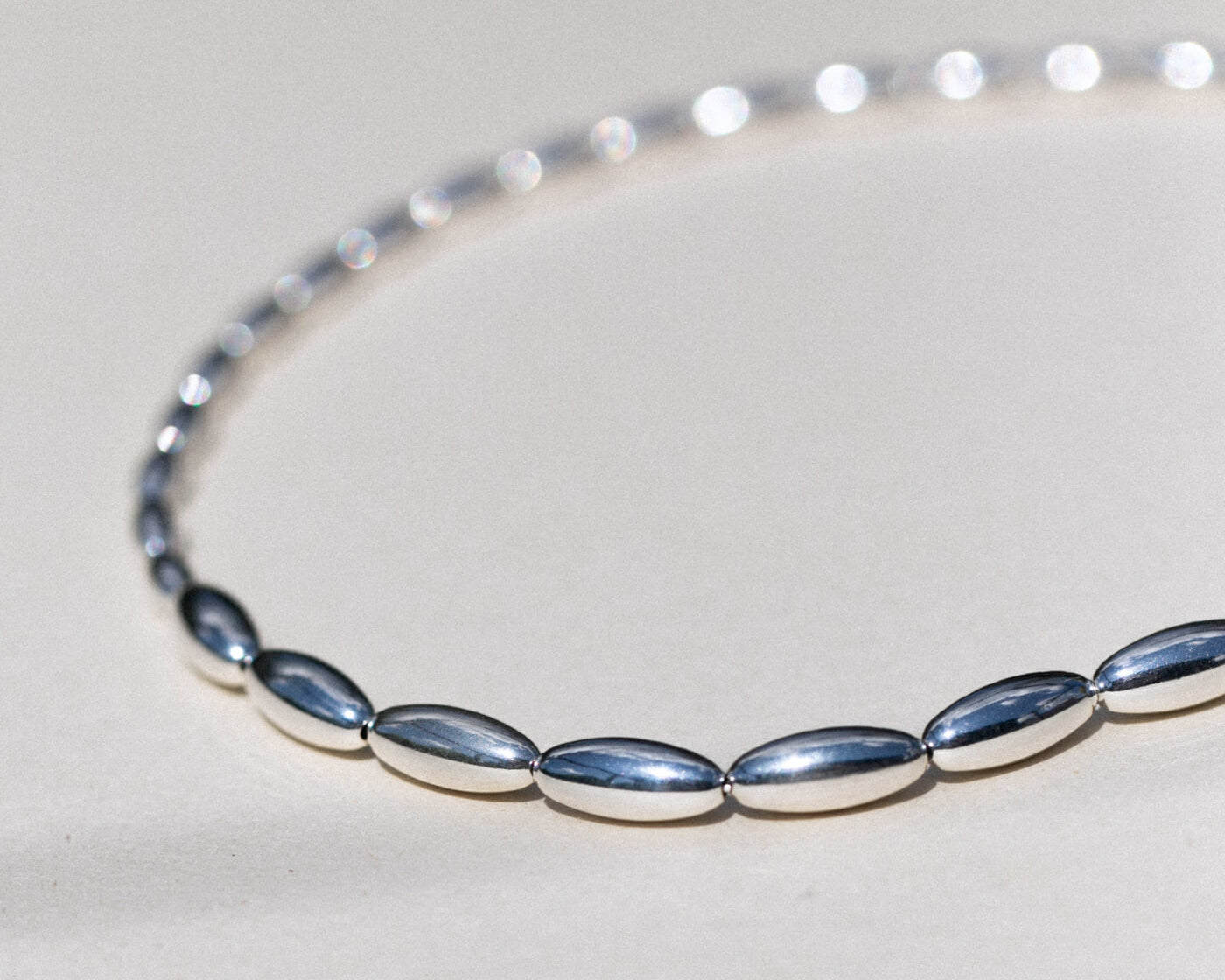 Silver beaded necklace on a light gray background