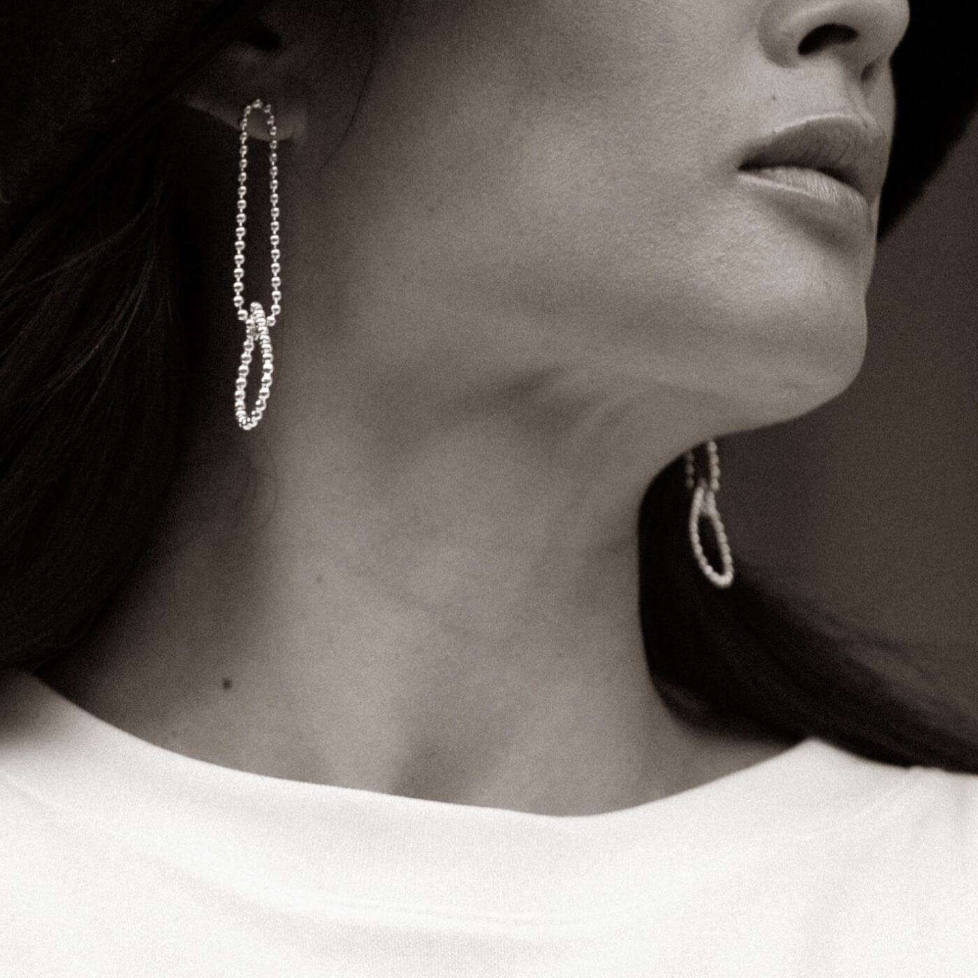 Close-up of a person wearing hoop earrings with a neutral background