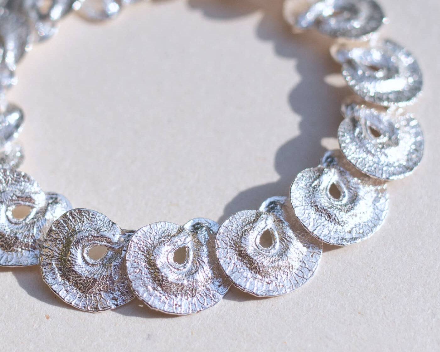 Silver bracelet with circular links on a light background