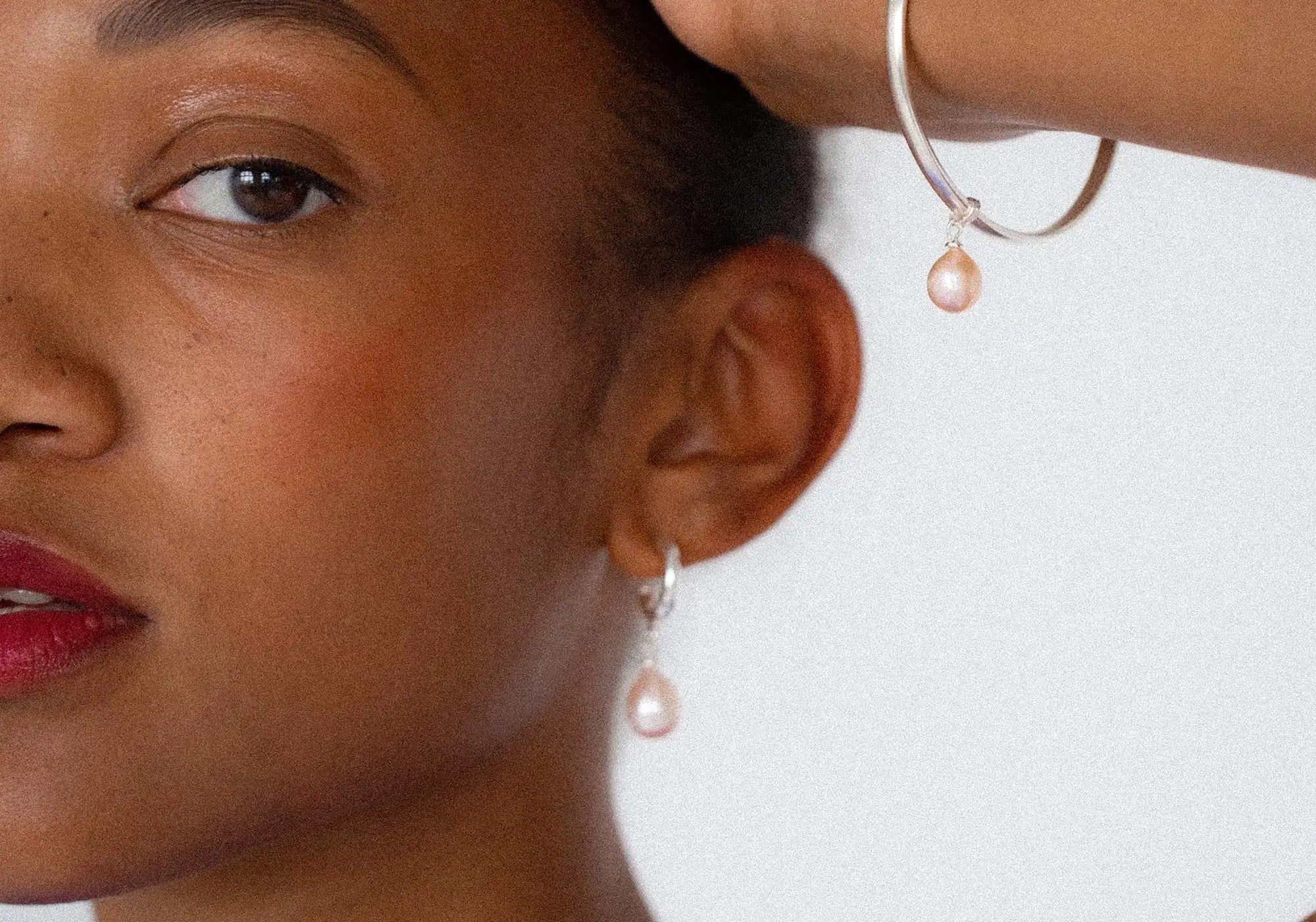 Close-up of a woman wearing pearl earrings with a blurred background